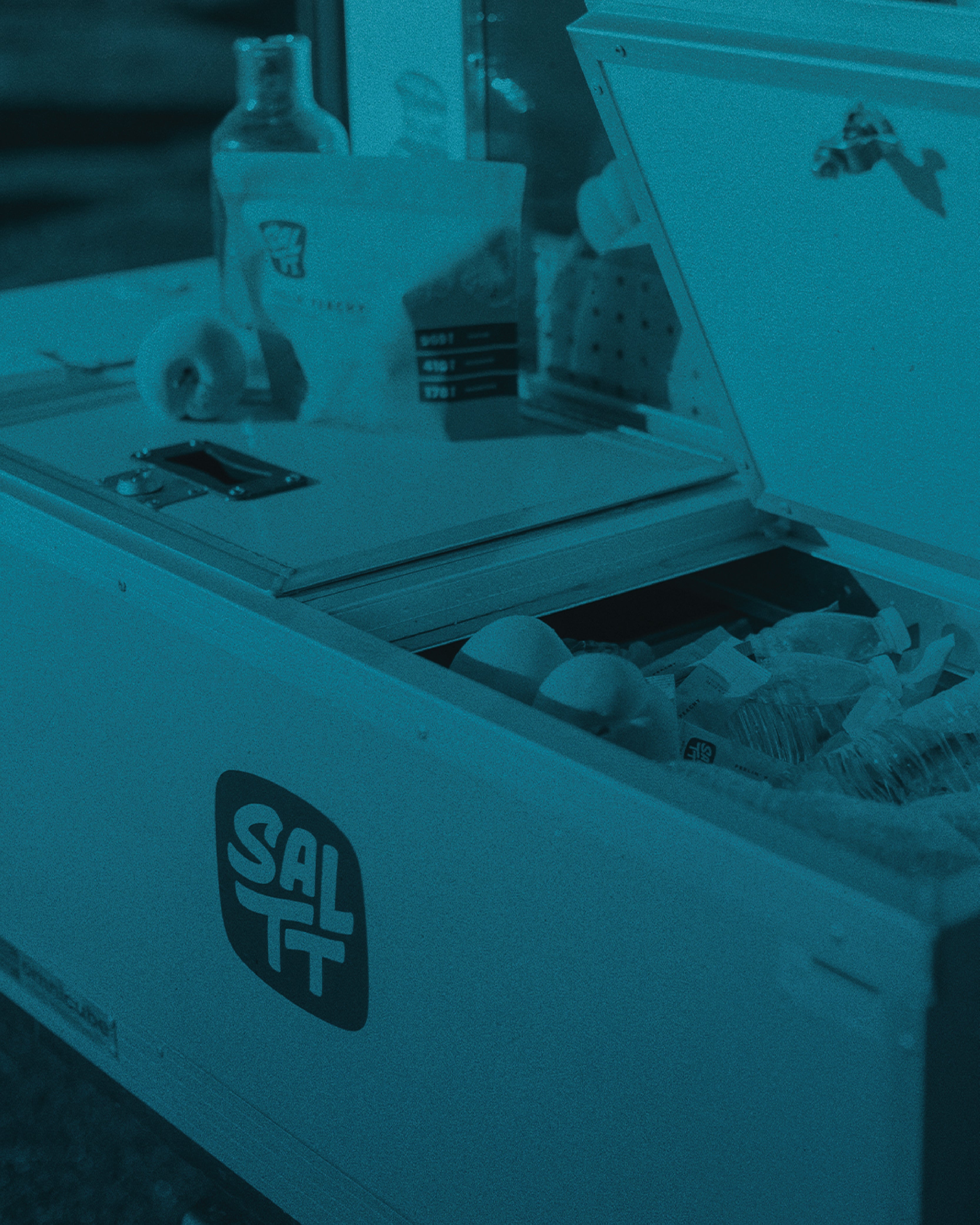 White SALTT Peachy Electrolytes single-serve stick packs, some covered in ice, in an open white cooler with the dark SALTT logo.