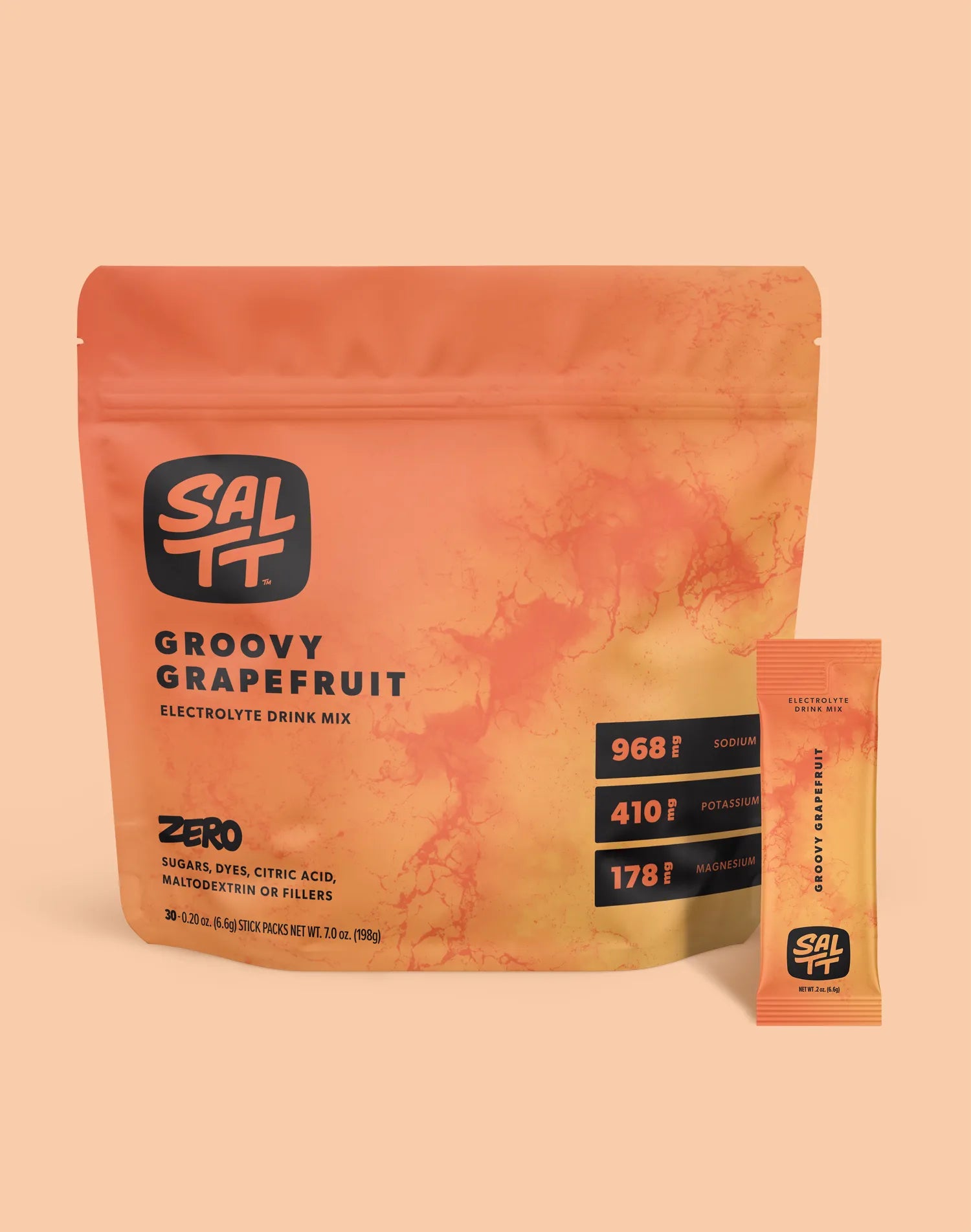 Orange SALTT Groovy Grapefruit Electrolyte Drink Mix stand-up pouch and individual stick pack. Both feature the SALTT logo and a reddish-orange ocean water splash pattern. The pouch specifies Groovy Grapefruit Electrolyte Drink Mix, ZERO SUGARS, DYES, CITRIC ACID, MALTODEXTRIN OR FILLERS, 968mg Sodium, 410mg Potassium, 178mg Magnesium, and 7.0 oz (198g) net weight. The stick pack details Groovy Grapefruit Electrolyte Drink Mix and 0.2 oz (6.6g) net weight.