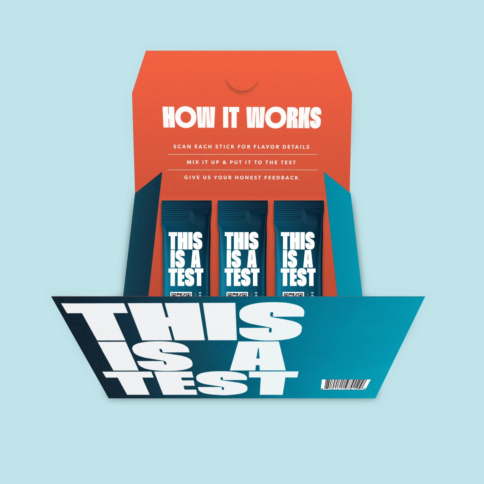 Open product packaging box with a dark teal base and an orange inner flap. It contains three dark teal stick packs. The box front and each individual stick pack display large white text THIS IS A TEST. The orange inner flap features white text HOW IT WORKS and multiple lines of usage instructions. A barcode is visible on the front of the box.