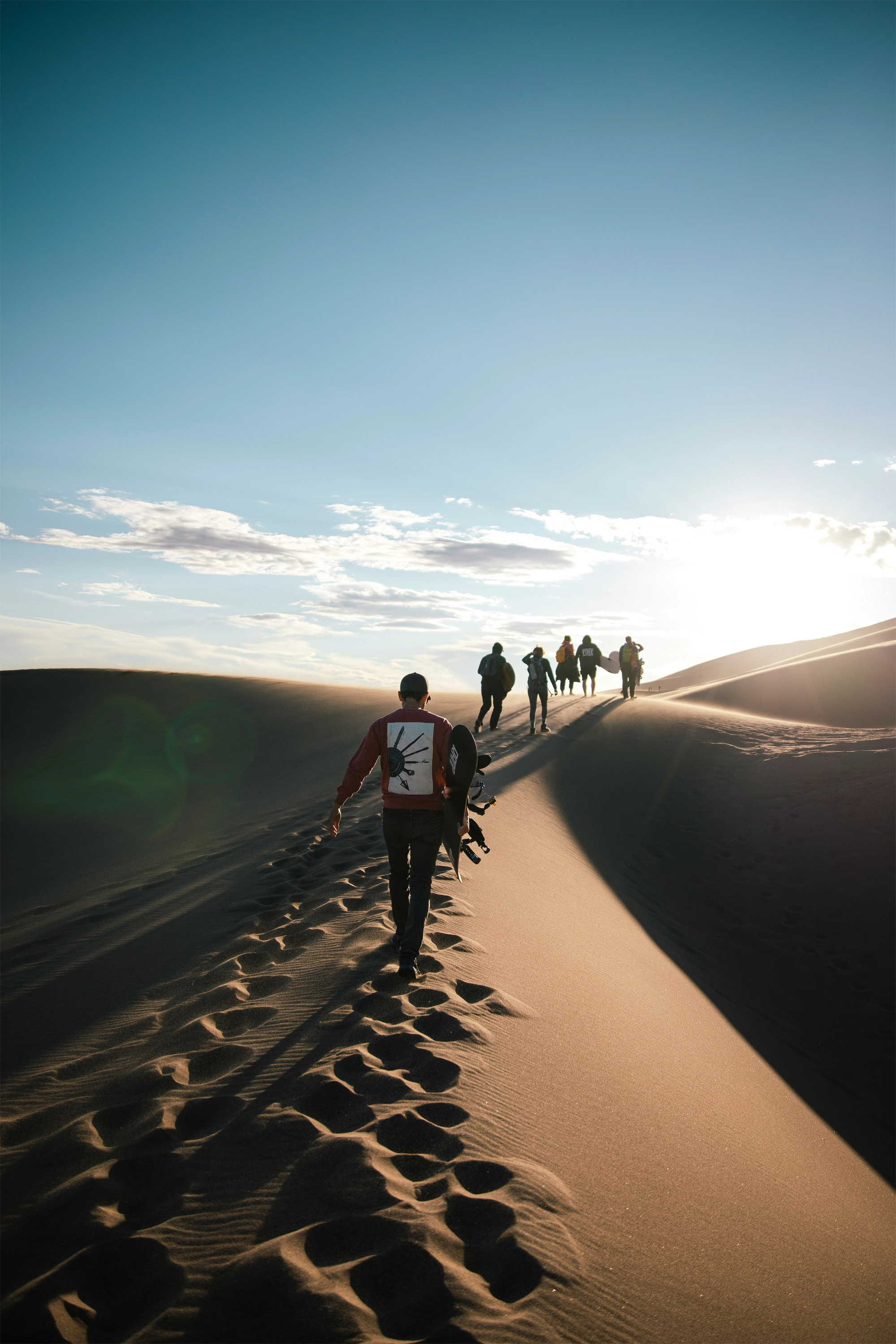 Group of friends about to snowboard down a sand dune