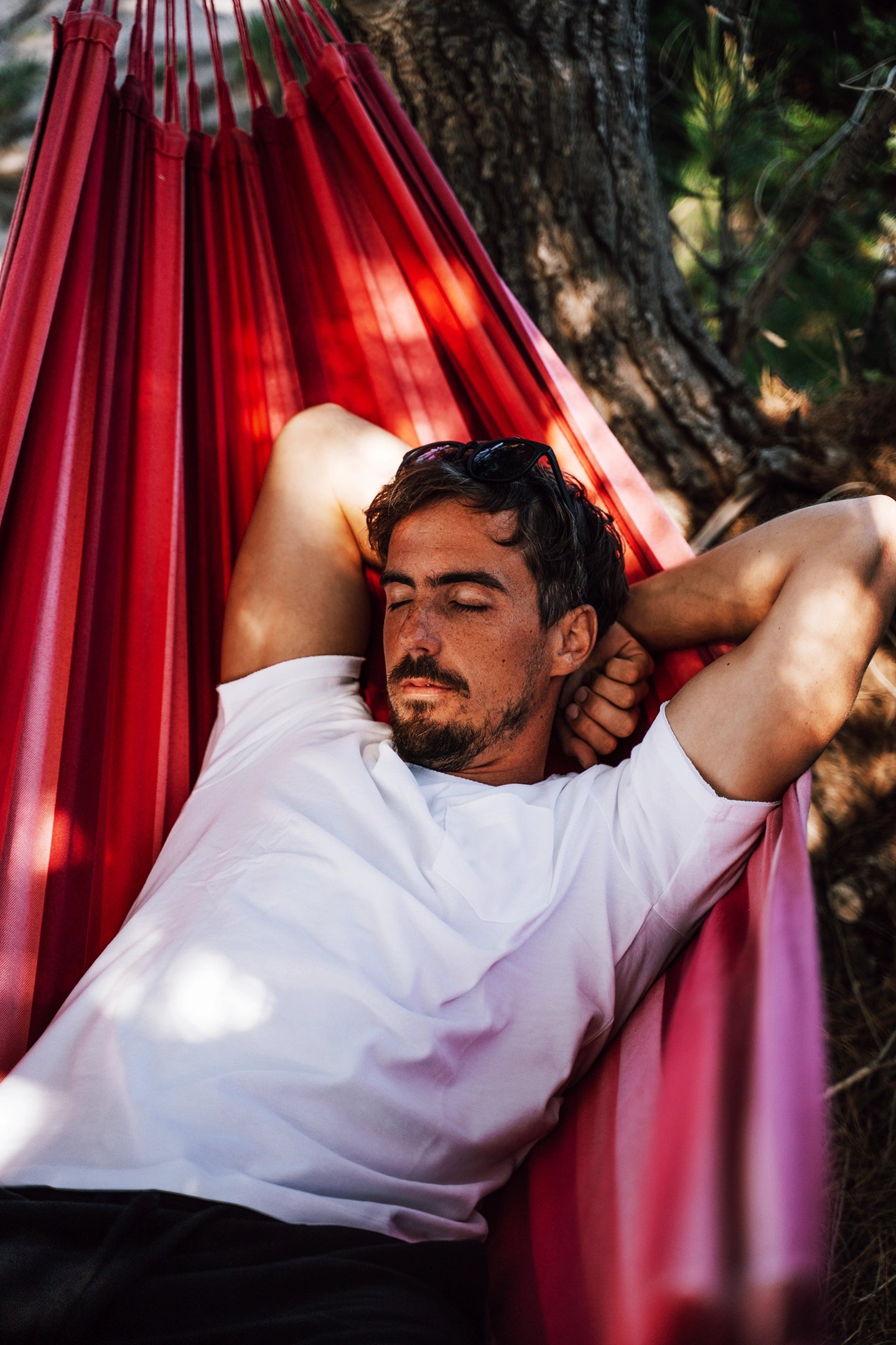 A waist up shot of a man relaxing on a hammock
