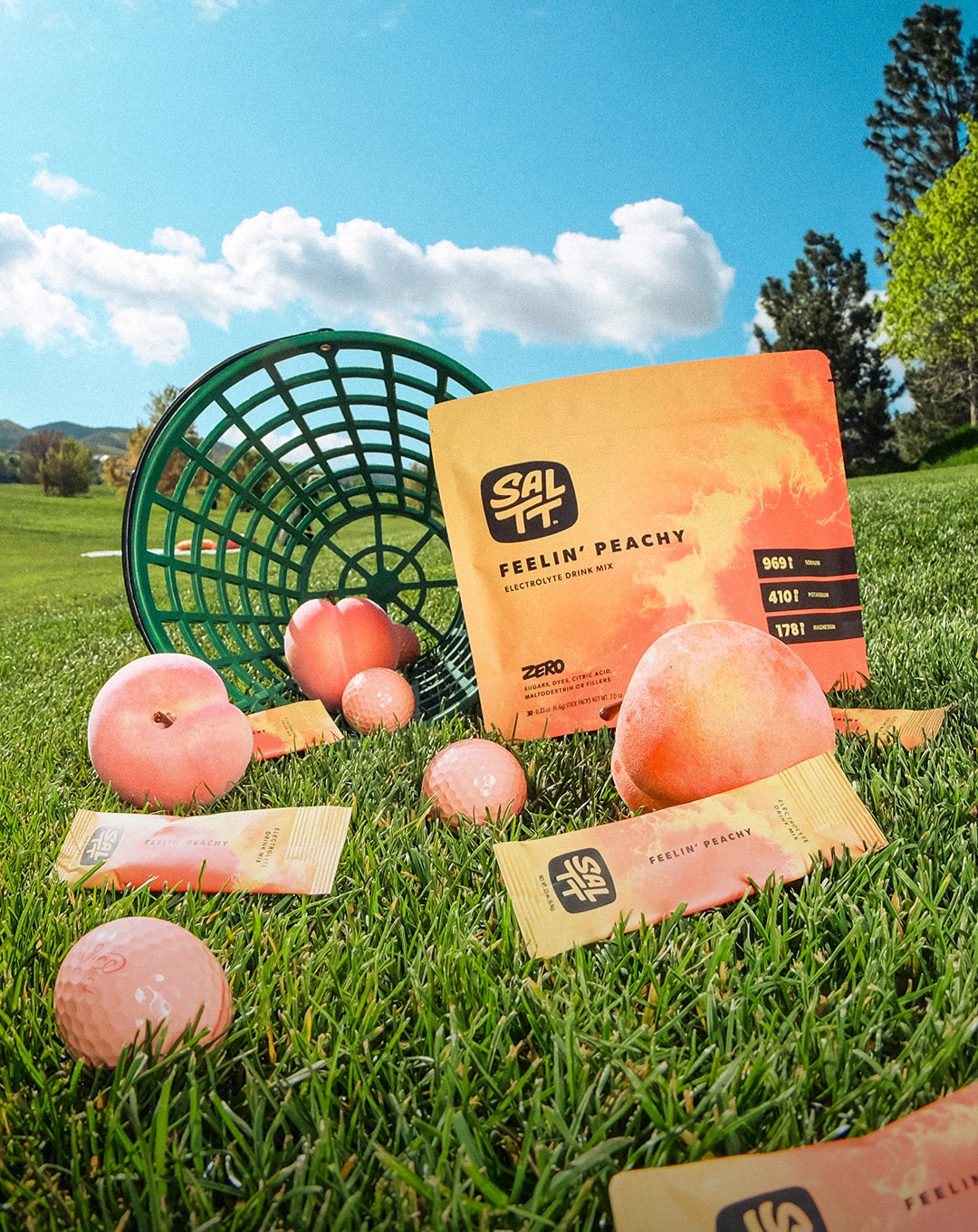 SALTY Feelin' Peachy sports drink mix packets on golf course with peaches