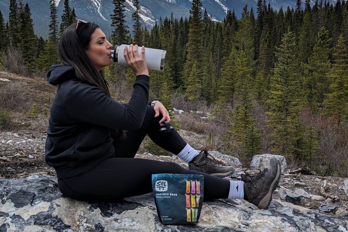 woman drinking SALTT in the wilderness
