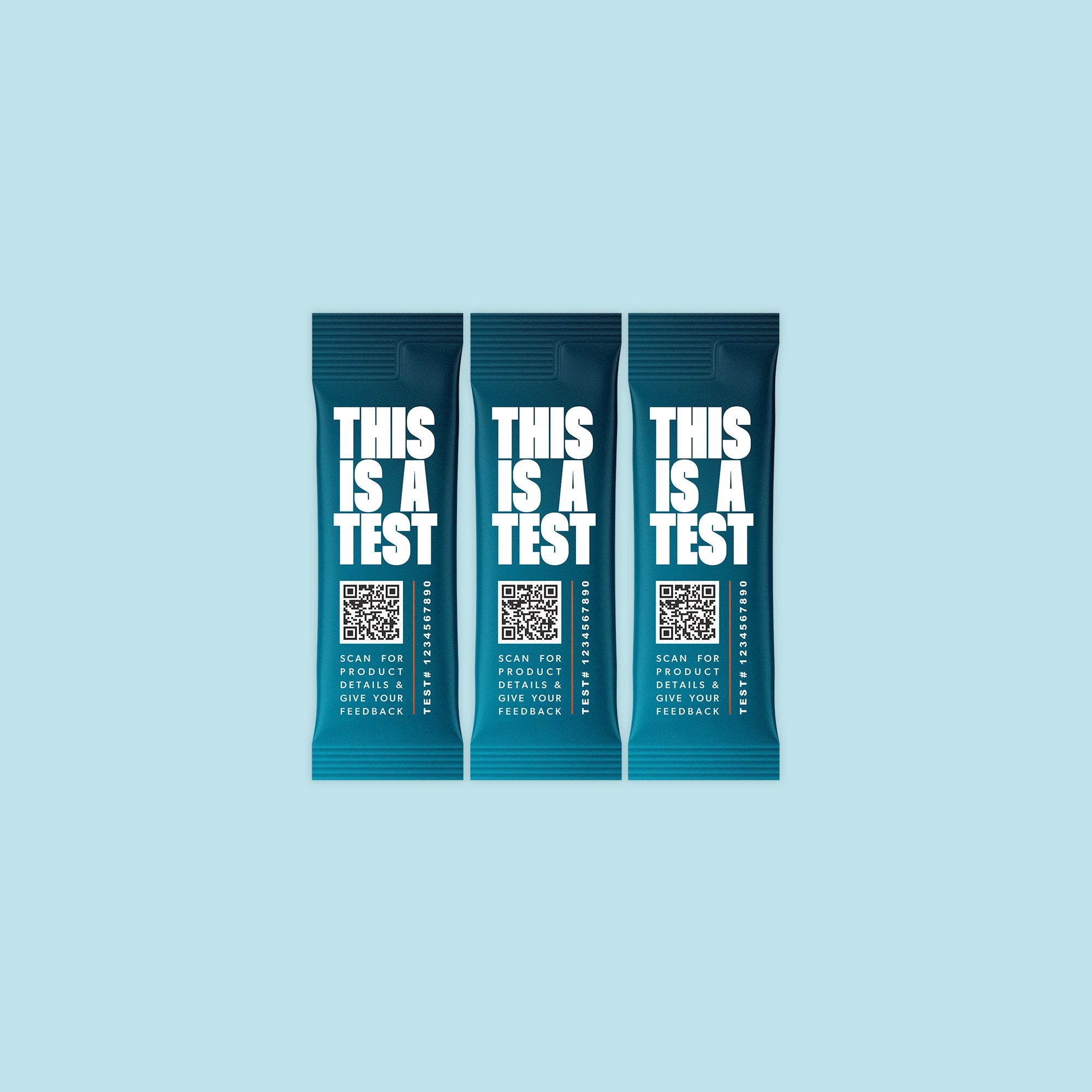 Three identical deep teal single-serve packets. Each features THIS IS A TEST in large white text, a QR code, the phrase SCAN FOR PRODUCT DETAILS & GIVE YOUR FEEDBACK, and TEST# 1234567890.