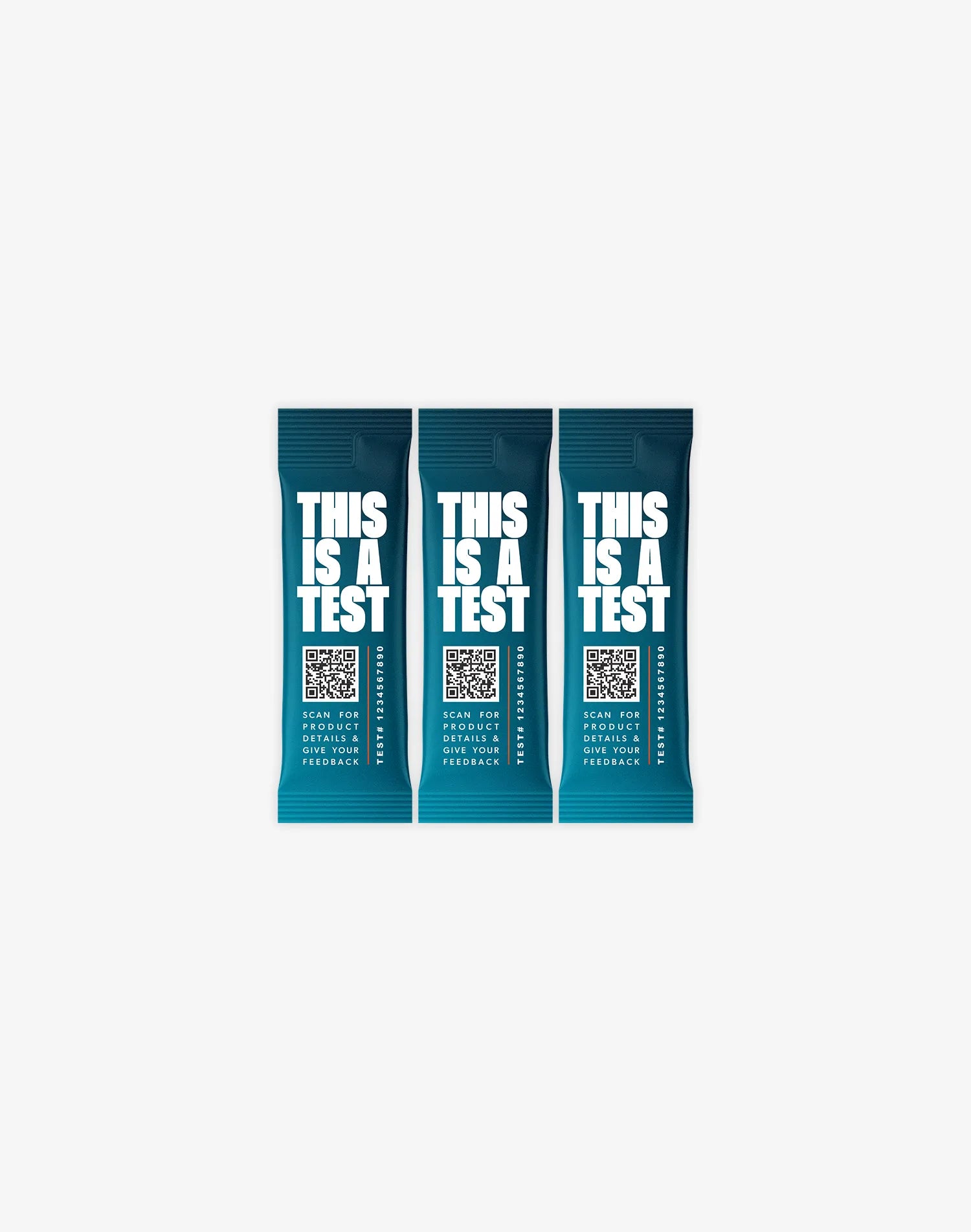 Three identical deep teal single-serve packets. Each features THIS IS A TEST in large white text, a QR code, the phrase SCAN FOR PRODUCT DETAILS & GIVE YOUR FEEDBACK, and TEST# 1234567890.