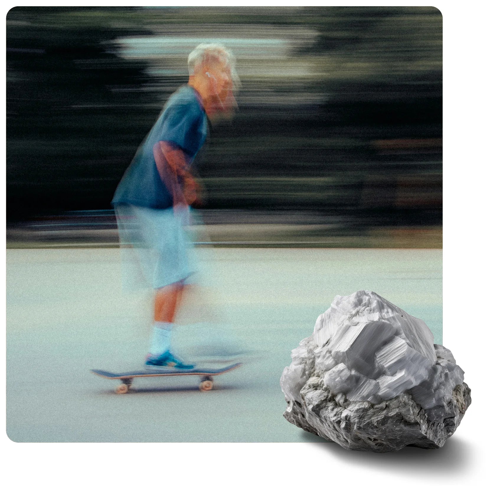 Blurred person on a skateboard on light pavement, dark streaky background. Large, rough cluster of white, crystalline minerals in foreground.