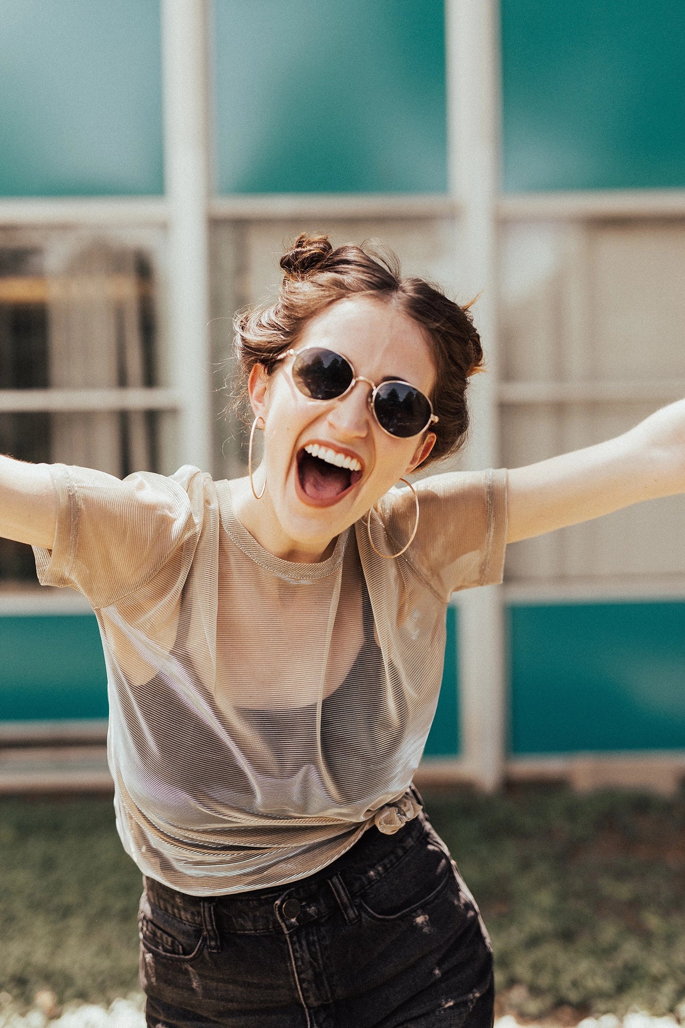 A woman smiling at the camera with her arms thrown out.